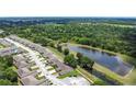 Wide aerial shot of a villa community adjacent to a tranquil pond surrounded by lush greenery and mature trees at 2724 Shelby Ruth Pl, St Cloud, FL 34769
