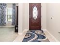 Inviting foyer featuring a decorative front door with glass insert, tile flooring, and a patterned area rug at 3349 Sagebrush St, Harmony, FL 34773