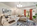 Bright living room featuring a sectional sofa, modern light fixture and natural light from a large window at 719 Stevelynn Cir, Winter Garden, FL 34787