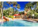 Resort-style pool features a slide, waterfall, lush landscaping, and inviting clear blue water at 936 Calabria Ave, Davenport, FL 33897