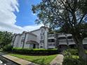 Three-story condo building with stucco exterior, red tile roof, and well-manicured landscaping at 13917 Fairway Island Dr # 931, Orlando, FL 32837