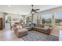 Bright living room featuring a large sectional sofa, ceiling fan, and ample natural light at 15241 Sunrise Grove Ct, Winter Garden, FL 34787