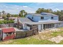 View of a fenced in backyard, patio, and some outbuildings with blue skies above at 1601 Randolph St, Deltona, FL 32725
