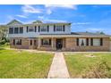 Two-story brick and siding home with a gray roof, dark shutters, and a sidewalk leading to the front door at 1601 Randolph St, Deltona, FL 32725