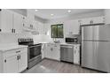 Modern kitchen with white cabinetry, stainless steel appliances, and a view through the window at 2 Rollingwood Trl, Deland, FL 32724
