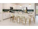 Modern, eat-in kitchen with white cabinets, stainless steel appliances, and stylish pendant lighting at 2500 Raghav Trail Cir, Tavares, FL 32778