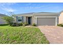 Inviting home with a well-kept lawn, complemented by a brick driveway and a two-car garage at 417 Tisone Ln, Davenport, FL 33837
