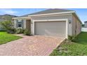 Attractive home showcasing a two-car garage, brick driveway, and lush green lawn at 417 Tisone Ln, Davenport, FL 33837