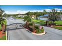 Gated entrance to a neighborhood featuring brick pillars, wrought iron gates, and mature landscaping at 4611 Cumbrian Lakes Dr, Kissimmee, FL 34746