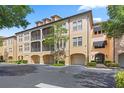 Exterior view of condo building with multiple levels, garage parking, screened porches, and mature landscaping at 500 Mirasol Cir # 203, Celebration, FL 34747