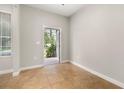 Bright, neutral room with tile floors, an open doorway, and a window providing natural light, waiting for personalization at 5911 Grassy Point Rd, Winter Garden, FL 34787