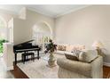Comfortable living room featuring a decorative rug, elegant furnishings, and natural light from the arched window at 6234 Tremayne Dr, Mount Dora, FL 32757