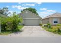 View of the home's exterior with a 2-car garage and a cracked concrete driveway at 8141 Golden Chickasaw Cir, Orlando, FL 32825