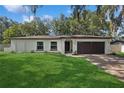 A well-manicured lawn enhances this charming single-story home with a dark brown garage door and trimmed landscaping at 898 Shed St, Oviedo, FL 32765