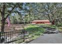 Secluded red home with a private drive, surrounded by mature trees and featuring an American flag at 127 Oak Ln, Ormond Beach, FL 32174