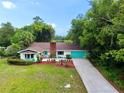An aerial view of a cozy single-story home with brick chimney, complemented by lush landscaping and mature trees at 1405 Periwinkle Ave, Deland, FL 32724