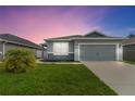 Charming single-Gathering home with a well-maintained lawn and a two-car garage at dusk at 141 Sandestin Dr, Haines City, FL 33844