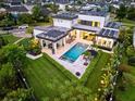 Aerial view showcases a modern home with a solar panel roof, pool, manicured lawn, and landscaping at 14106 Eliot Ave, Orlando, FL 32827