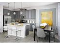 Modern kitchen with gray cabinets, stainless steel appliances, a kitchen island with barstool seating, and adjacent dining area at 2524 Raghav Trl, Tavares, FL 32778