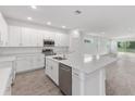 Bright open kitchen featuring a large island, stainless steel appliances, and sleek white cabinets at 2530 Raghav Trl, Tavares, FL 32778