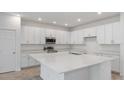 Spacious kitchen with white cabinets, stainless steel appliances, a large center island, and a double sink at 2533 Raghav Trl, Tavares, FL 32778