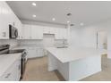 Bright kitchen with an island, stainless steel appliances, and white cabinets at 2533 Raghav Trl, Tavares, FL 32778