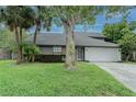 Home exterior showcasing a well-kept lawn, mature trees, and a two car garage at 359 Westwind Ct, Lake Mary, FL 32746