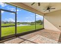 Screened lanai offering scenic views of the lake and landscaping, complete with a ceiling fan and brick flooring at 3847 Shoreside Dr, Kissimmee, FL 34746