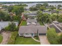 An aerial view shows a single-story home on a large lot with a lake view, a screened-in patio, and mature landscaping at 3902 Brandeis Ave, Orlando, FL 32839
