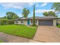 Charming single-story home featuring a well-manicured lawn, a blue front door, and a gray two-car garage at 3902 Brandeis Ave, Orlando, FL 32839