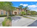 Charming two-story townhome featuring a concrete driveway, lush landscaping and a welcoming arched entryway at 3938 Calabria Ave, Davenport, FL 33897