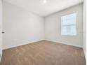 A bright, carpeted bedroom features a window and a neutral color scheme at 437 Caribbean Ct, Kissimmee, FL 34759