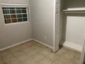 Clean and simple bedroom with a built-in closet, tile floors, and natural light at 6113 Hialeah St, Orlando, FL 32808