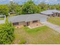 Aerial view of single-story home with red window trim and concrete driveway in a lush neighborhood at 964 Clayton Dr, Deltona, FL 32725
