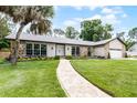 Inviting home featuring a manicured lawn, stone details, and a brick walkway leading to the entrance at 107 Laurel Oak Dr, Longwood, FL 32779