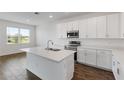 Well-lit kitchen featuring white cabinets, an island with a stainless steel sink, and stainless steel appliances at 3144 Suraj Cir, Tavares, FL 32778