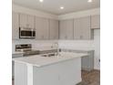 Modern kitchen with sleek gray cabinetry, stainless steel appliances, and a spacious quartz island at 3144 Suraj Cir, Tavares, FL 32778