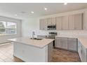 Bright kitchen featuring gray cabinets, stainless steel appliances, and a large island with a double sink at 3144 Suraj Cir, Tavares, FL 32778