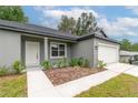 Attractive home featuring a manicured lawn, mulch beds, light gray paint, and an attached two-car garage at 327 Larch Rd, Ocala, FL 34480
