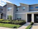 Contemporary two-story townhouse with stone accents, manicured landscaping, and a sidewalk leading to a covered entrance at 456 Ocean Course Ave, Davenport, FL 33896
