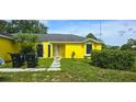 A well-lit view of the front exterior with lush green lawn of the yellow house at 4719 Miranda Cir, Orlando, FL 32818