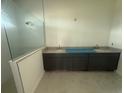 Sleek bathroom featuring double sinks, dark cabinets, granite countertops, and a glass-enclosed shower at 10224 Fiddley Aly, Orlando, FL 32827