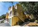 Beautiful yellow townhouse with a staircase leading to a balcony and well-kept landscaping at 12106 Poppy Field Ln # 107, Orlando, FL 32837