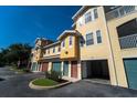 Bright yellow townhouse complex with well-maintained landscaping, garages, and inviting entrances at 12106 Poppy Field Ln # 107, Orlando, FL 32837