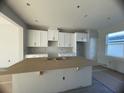 Bright, unfinished kitchen featuring white cabinets, an island covered with cardboard, and a view to the back at 1356 Lumpini St, St Cloud, FL 34771