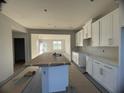 Bright, unfinished kitchen featuring white cabinets, an island covered with cardboard, and a view to the back at 1356 Lumpini St, St Cloud, FL 34771