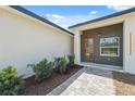 Close-up of the home's entryway, showcasing a wooden front door with glass panels and manicured landscaping at 14930 Sw 66Th Ave Rd, Ocala, FL 34473