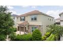 Charming tan two-story home with a brick driveway and a two-car garage surrounded by mature trees and landscaping at 1505 Nassau Point Trl, Kissimmee, FL 34747