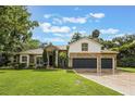 Lovely home featuring a three-car garage, stone accents, and a lush green lawn at 1874 Royal Majesty Ct, Oviedo, FL 32765