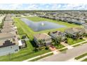 Aerial view of a gray home with a brick driveway, complemented by a serene pond with a fountain in a planned community at 2431 Tudor Rose Dr, Sanford, FL 32773